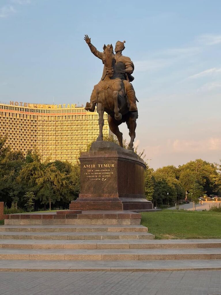 statue of Amir Temur on a horse in the center of a square with Hotel Uzbekistan in the background, Tashkent, as featured in our guide about where to stay in tashkent.
