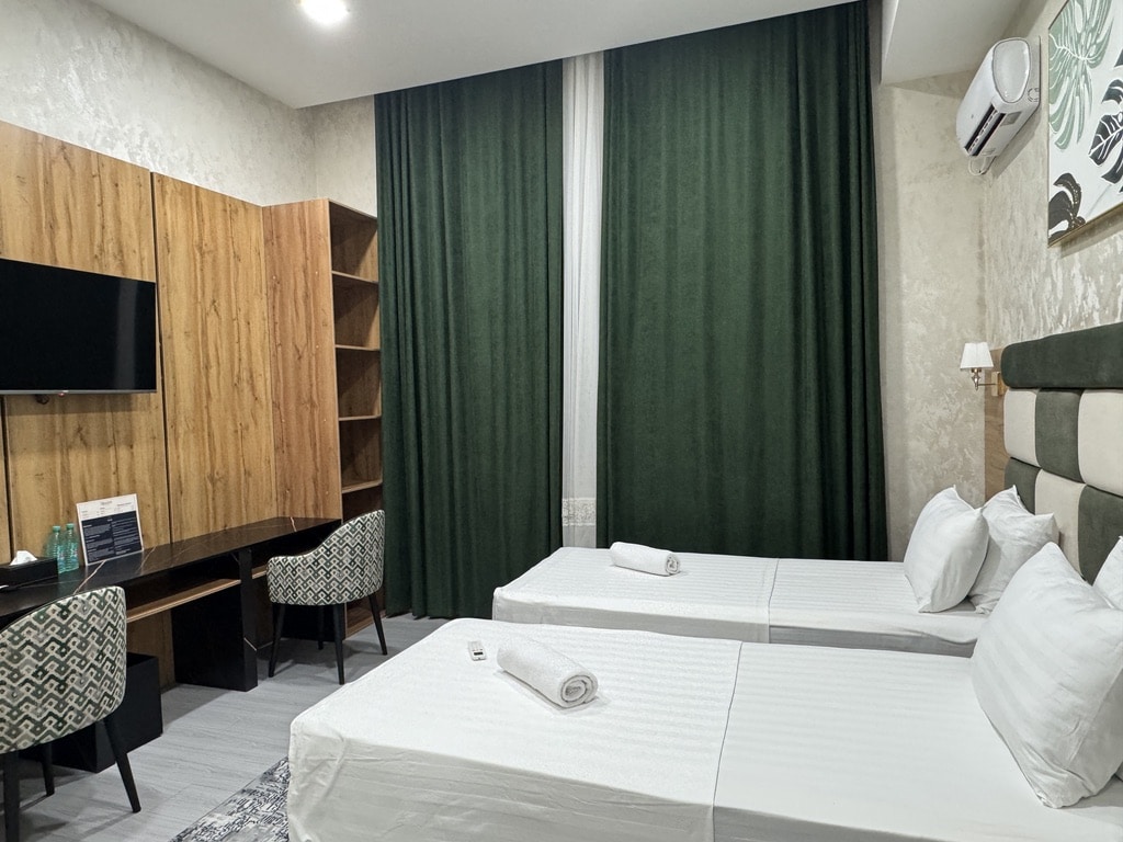 double room at avant hotel in tashkent, uzbekistan with dark green curtains and brown and green designs