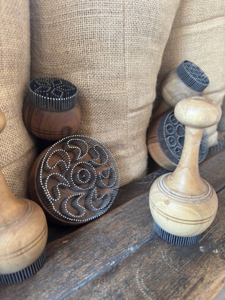 A close-up shot of traditional wooden Uzbek bread stamps, known as chekich, showing the intricate metal pin patterns used to design the center of non flatbread in Bukhara.