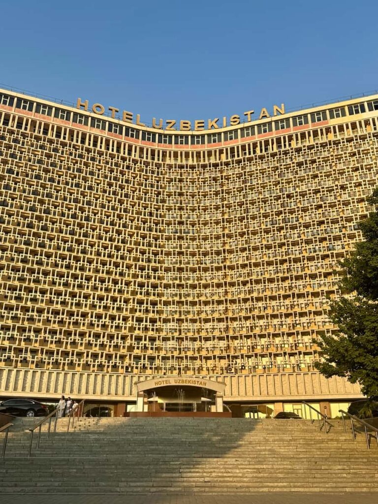 The iconic Soviet architecture of Hotel Uzbekistan and its geometric staircase facade at sunset, from our Tashkent travel guide