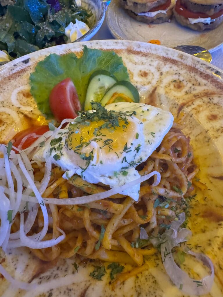 close up shot of stir-fried lagman dish with a fried egg on top and onions at a restaurant in bukhara