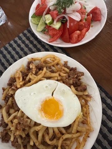 traditional laghman dish of uzbekistan with stir fried noodles, minced meat and fried egg on top