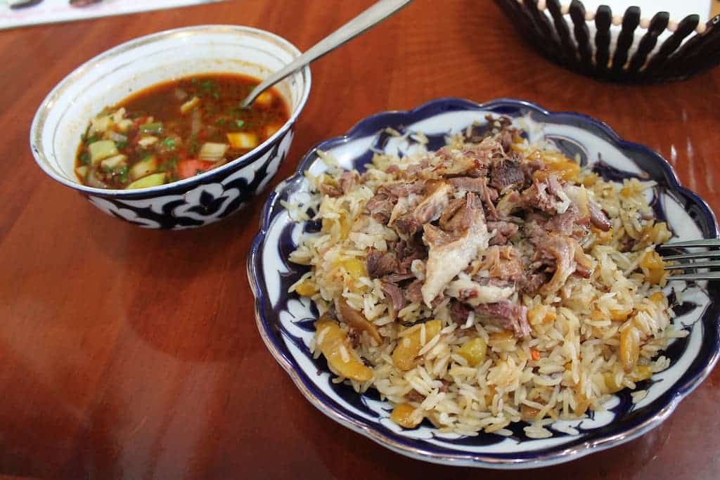 A close-up shot of a traditional Uzbek plov dish served with a side of herb soup, a must-try culinary experience highlighted in our Uzbekistan travel guide.