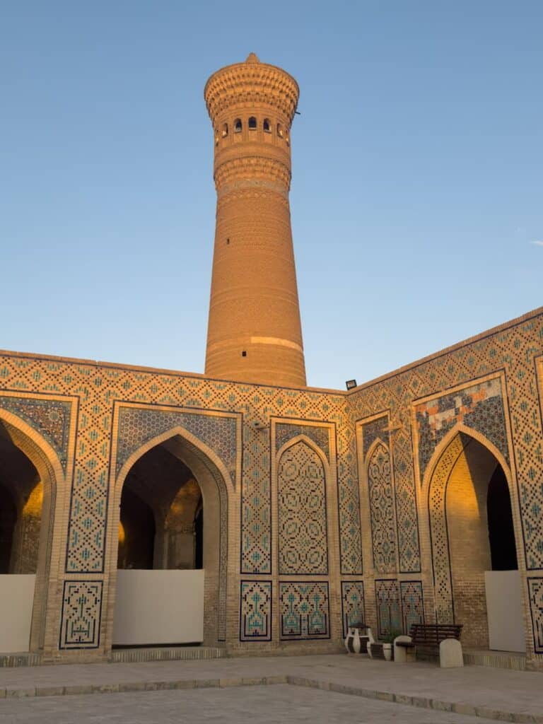 Low-angle view looking up at the historic brick Kalan Minaret in the Po-i-Kalyan complex of Bukhara, Uzbekistan, showcasing its detailed geometric brickwork patterns