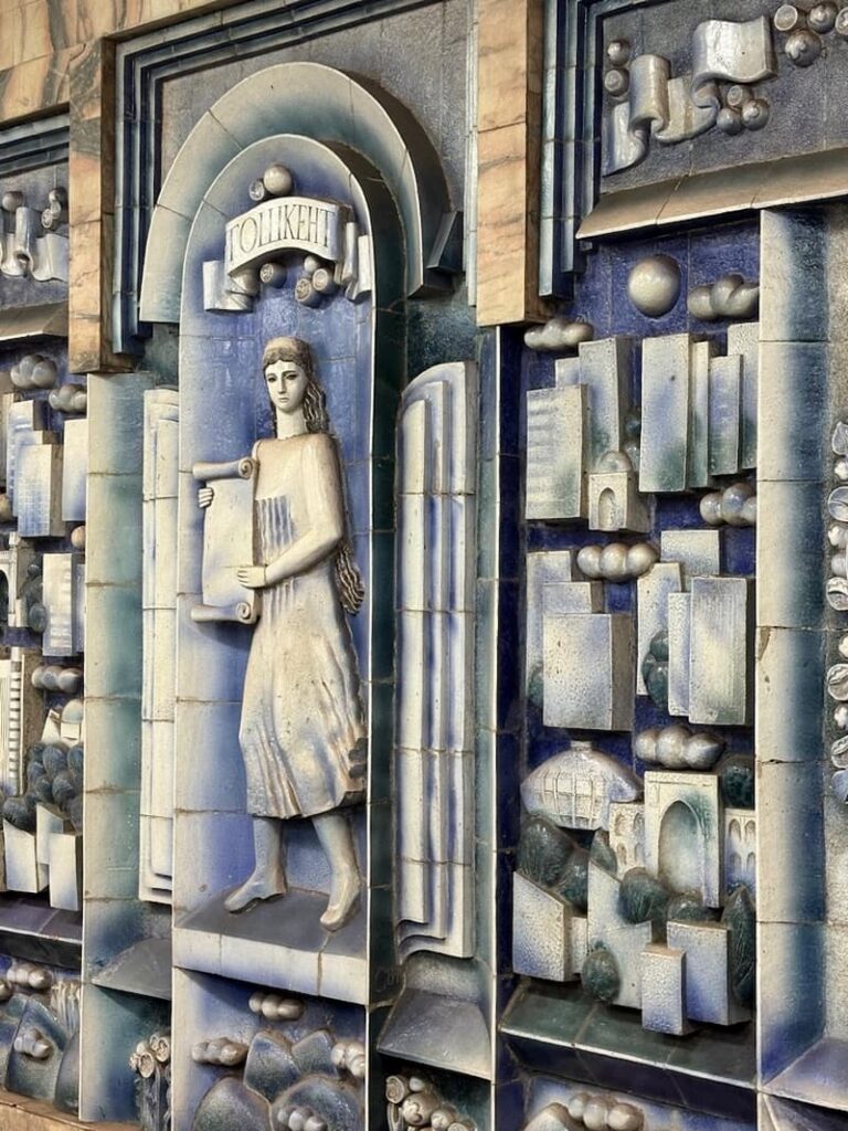 white and blue mosaic of a girl holding a papyrus at tashkent metro station in tashkent, uzbekistan