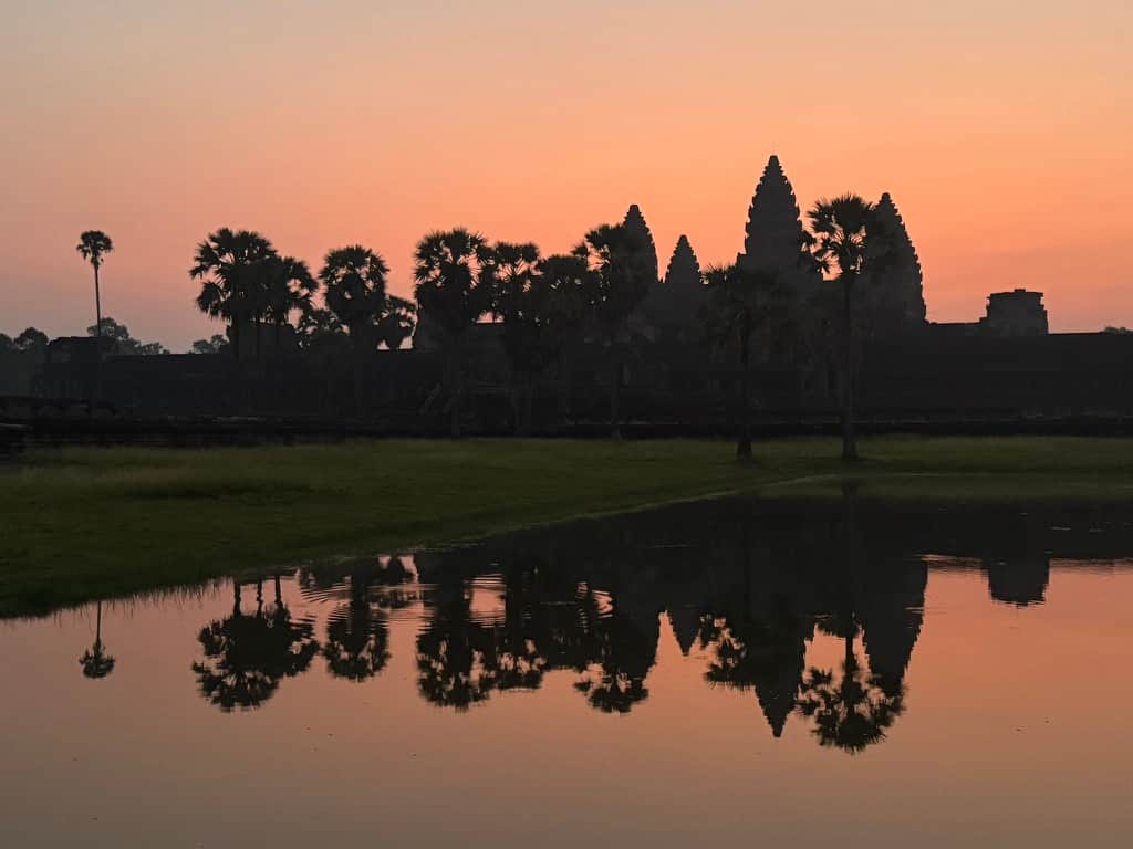 Stunning sunrise behind the main towers of Angkor Wat temple in Siem Reap reflecting over a pond, Cambodia.