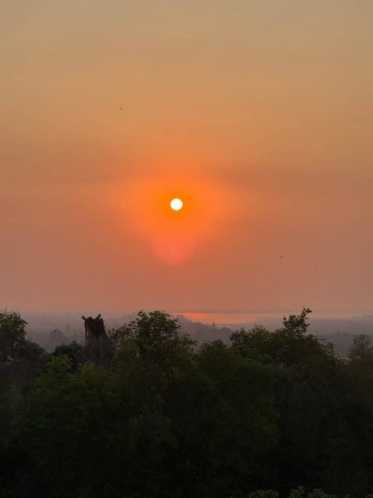 Sunset view over the jungle treetops from the hilltop of Phnom Bakheng temple in Cambodia.