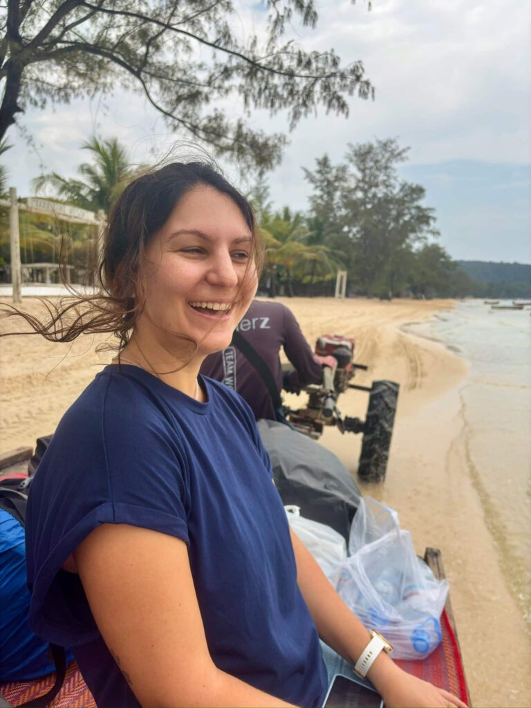 Eleni, the author of this blog, laughing and enjoying the ride on a beach transport cart during a tropical island getaway in Cambodia.