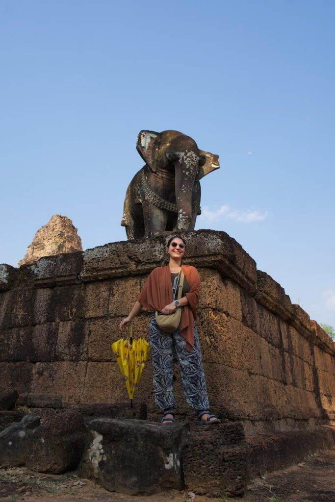 Traveler posing next to a historic stone elephant statue at the Eastern Mebon temple ruins.