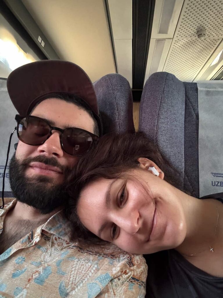 Eleni and Ale, the authors of this travel blog, sleeping on a train in Uzbekistan during a long transit day