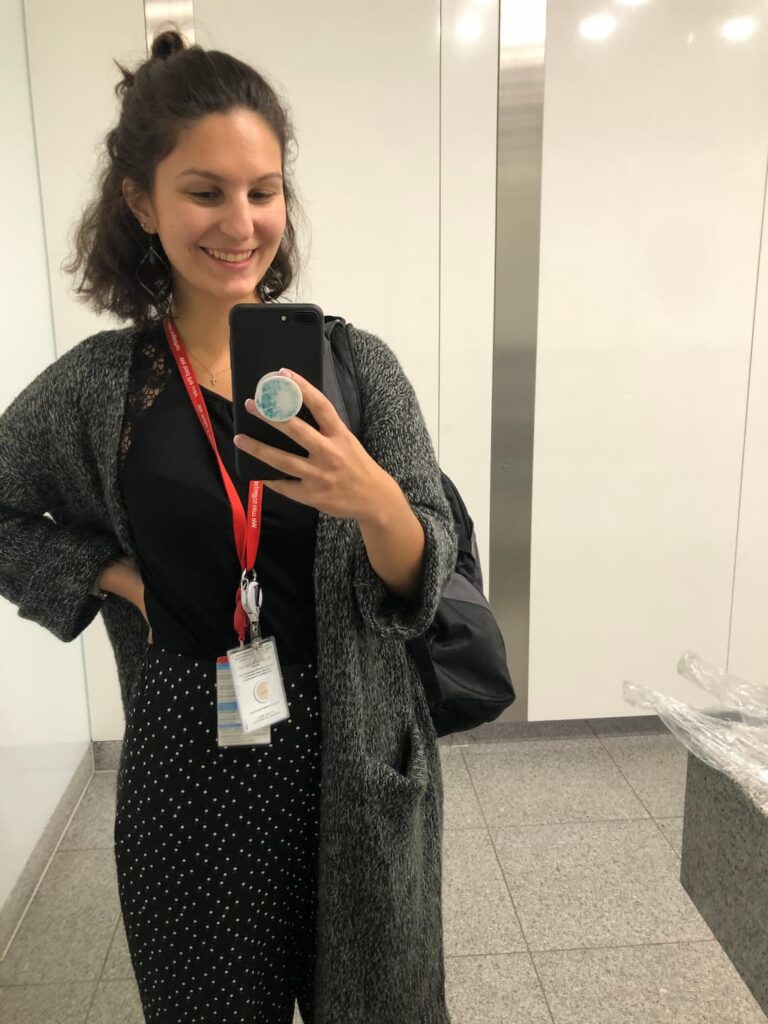 the author taking a selfie at her former business premises in London while having a business lanyard around her neck