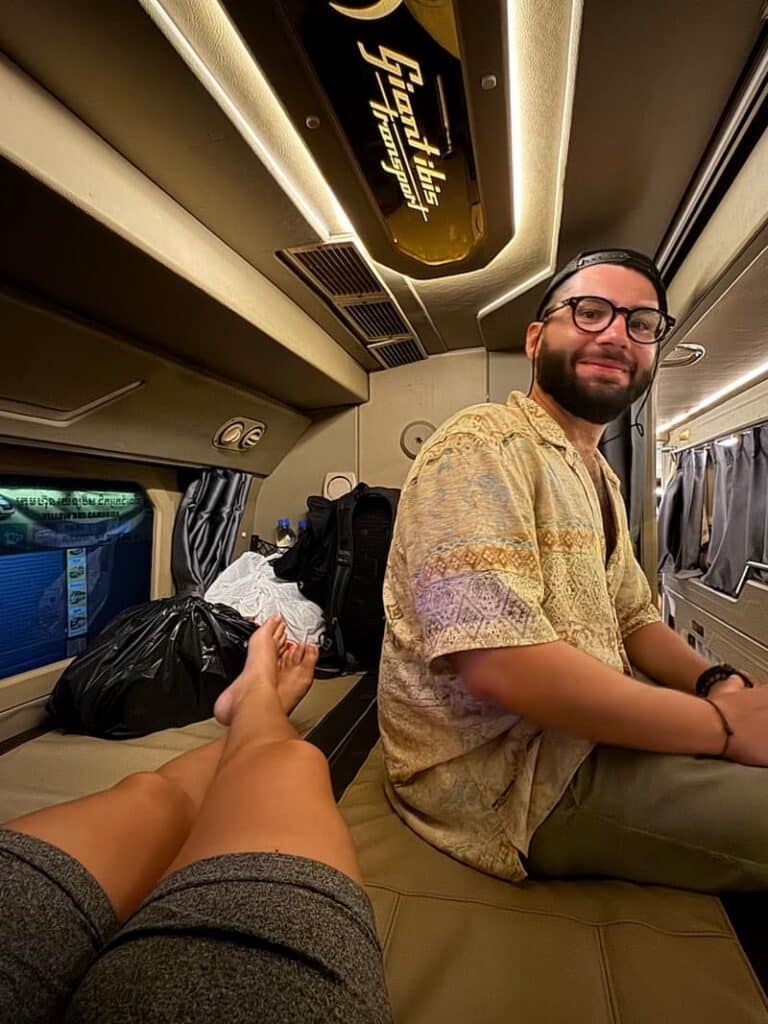 Ale and another passenger relaxing inside a shared sleeper cabin on a Giant Ibis transport bus.