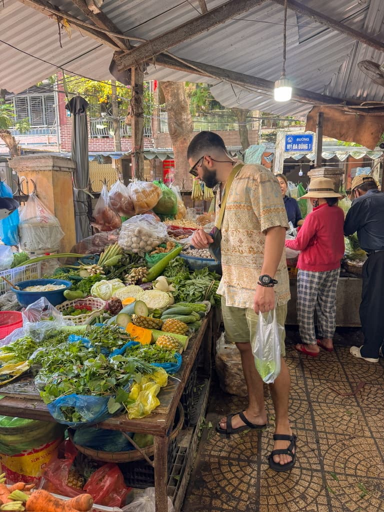 Ale, one of the authors of this travel blog, selecting fresh veggetables from a local market in Da Nang, Vietnam