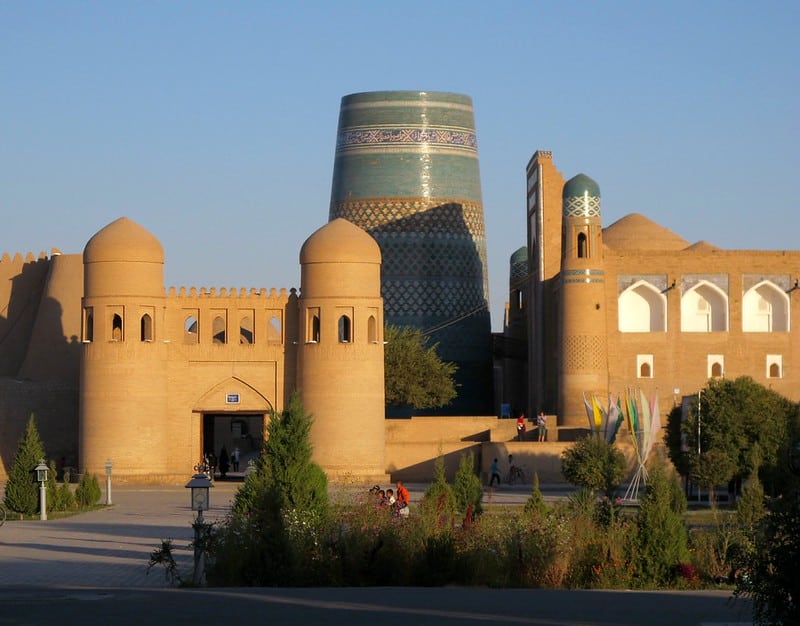 The iconic turquoise Kalta Minor Minaret towering over the ancient mud-brick walls and gate of Itchan Kala in Khiva, Uzbekistan.
