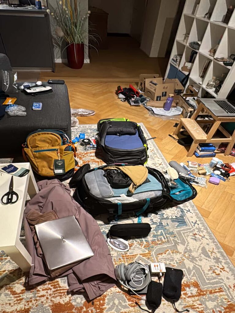living room floor full of items to be sorted, backpacks, and traveling gear to be decluttered before moving out