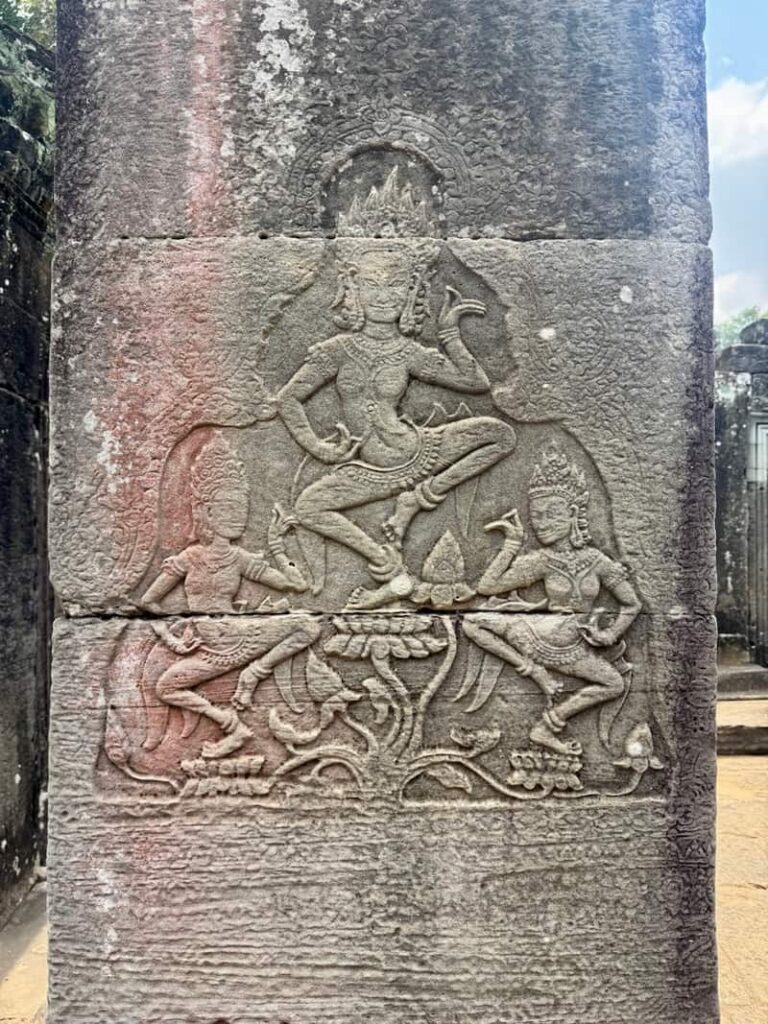 Close-up of ancient Khmer stone pillar carvings depicting dancing celestial figures at Angkor Wat.