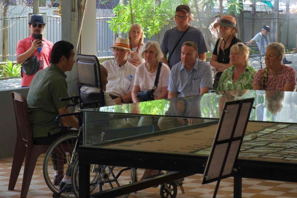 S-21 survivor Bou Meng in a wheelchair speaking through an interpreter to a group of international tourists at the Tuol Sleng Genocide Museum in Phnom Penh.