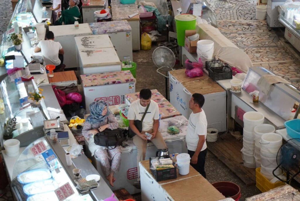 High-angle view of vendors and shoppers at a food stall inside Chorsu Bazaar in Tashkent