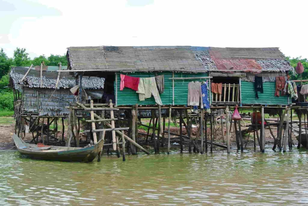 Traditional wooden stilted houses over the water with a moored boat at the Kompong Khleang fishing village near Siem Reap, Cambodia.