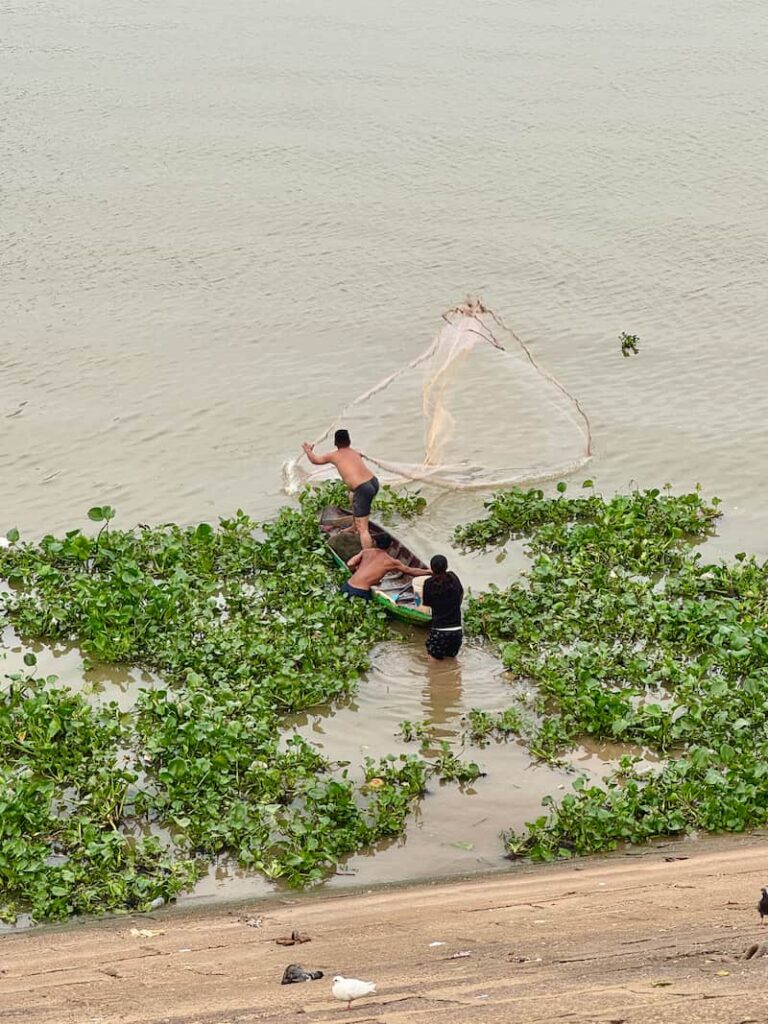 Catching a glimpse of local life and fisherman casting a net from a boat along the Mekong River