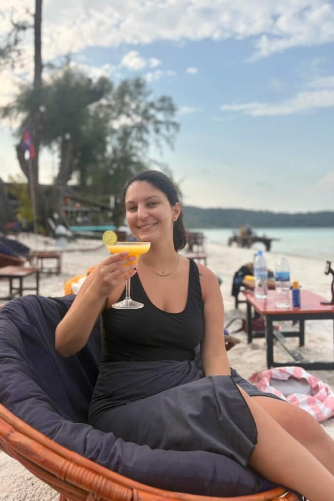 One of the authors of this travel blog relaxing with a cocktail in a lounge chair on the white sand beach of Koh Rong Samloem.