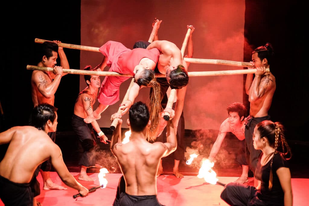 Performers executing a dramatic acrobatic stunt with bamboo poles and fire during a live show at Phare, The Cambodian Circus in Siem Reap, Cambodia.