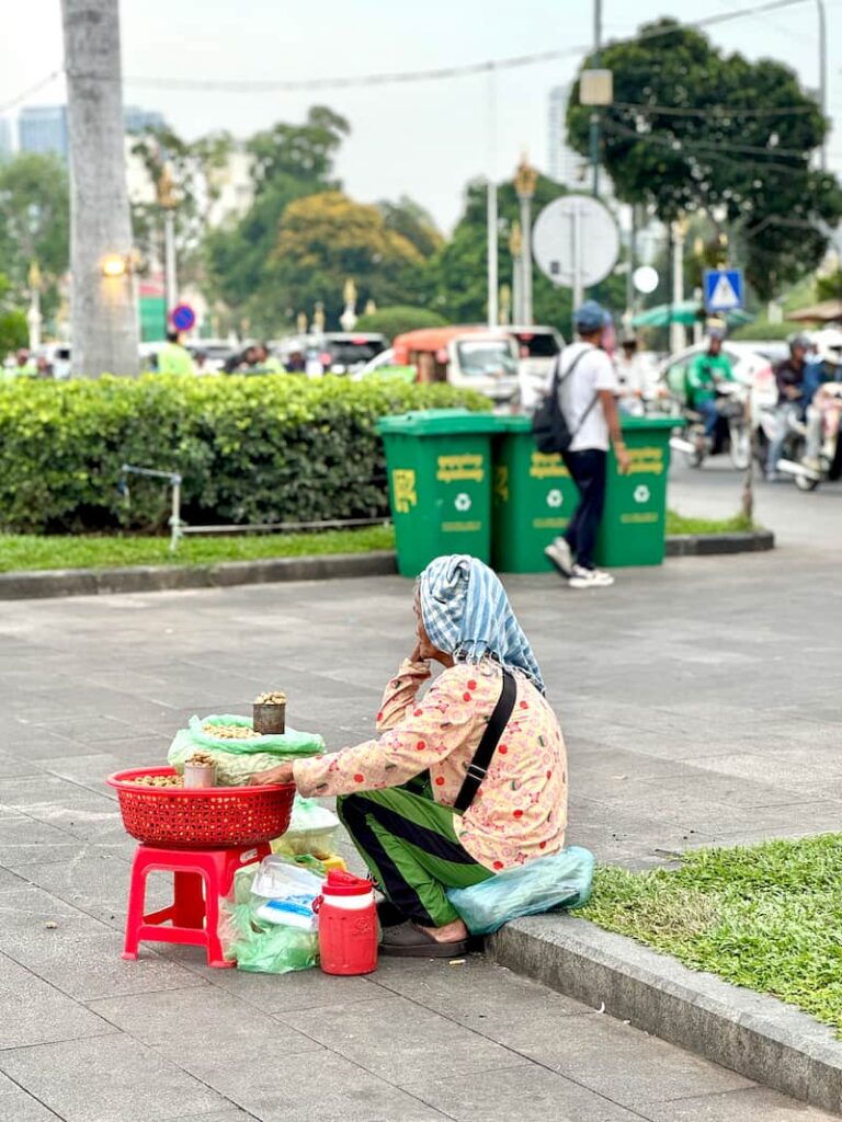 A local vendor selling traditional snacks on the busy sidewalks of Phnom Penh, encountered while spending 10 days in Cambodia.