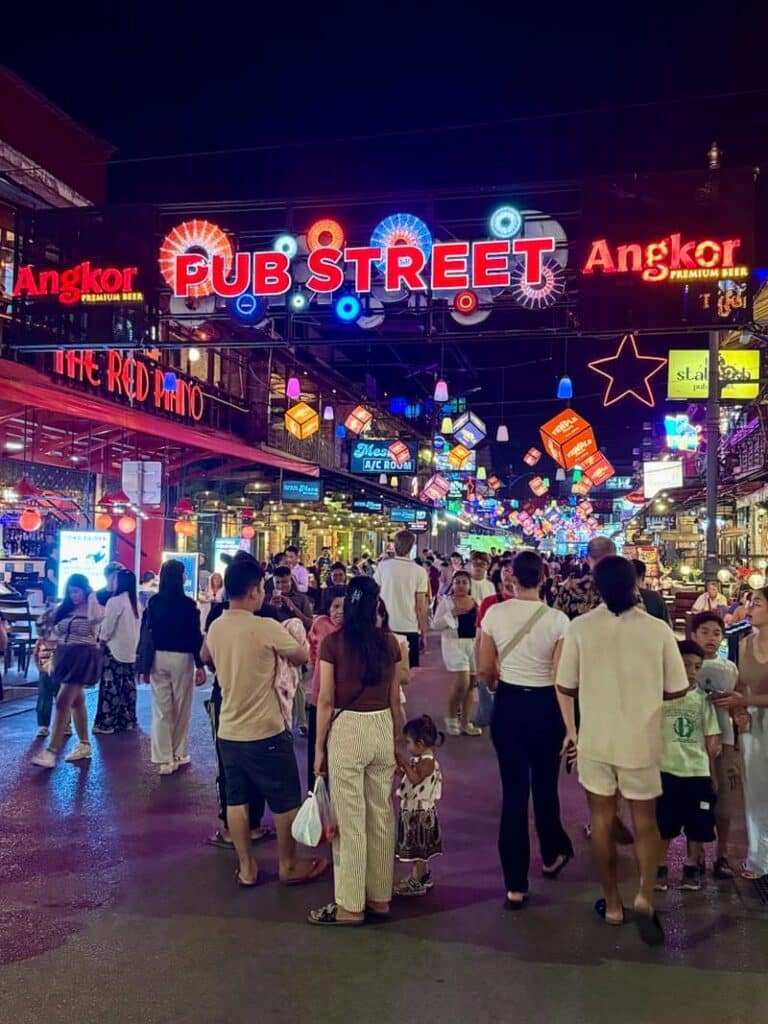 Crowds of people walking down the neon-lit Pub Street in Siem Reap, Cambodia at night.