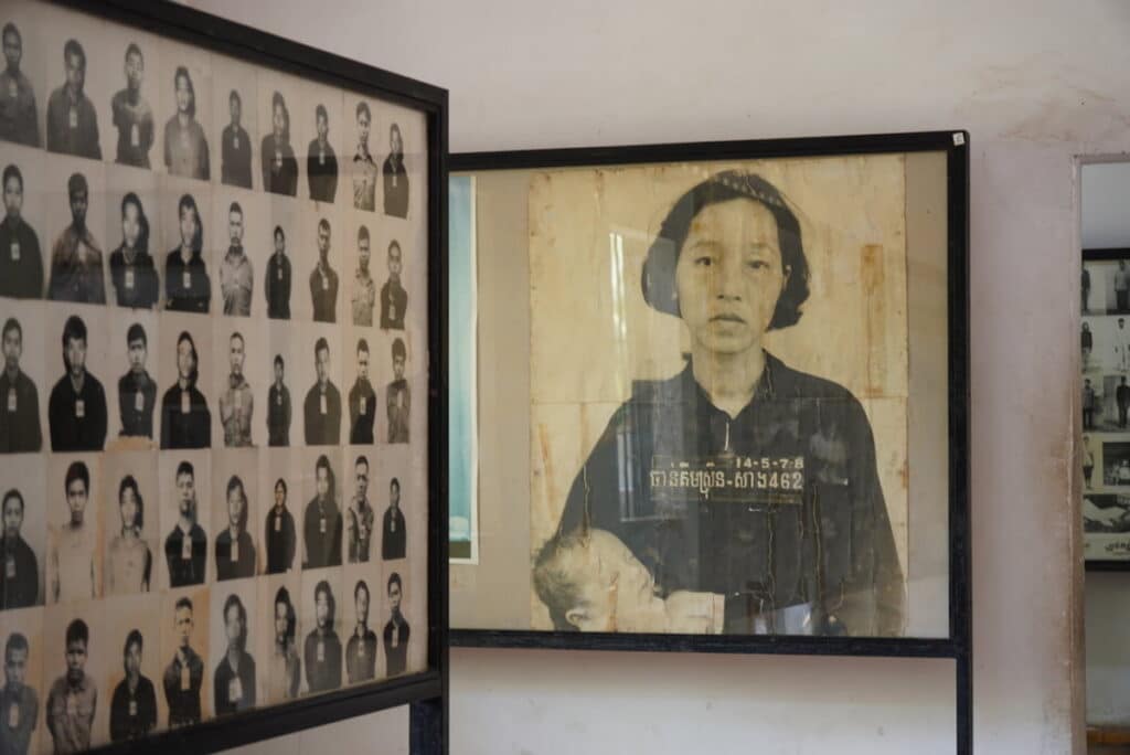 Exhibition wall featuring historical black-and-white prisoner ID photographs inside the Tuol Sleng Genocide Museum.