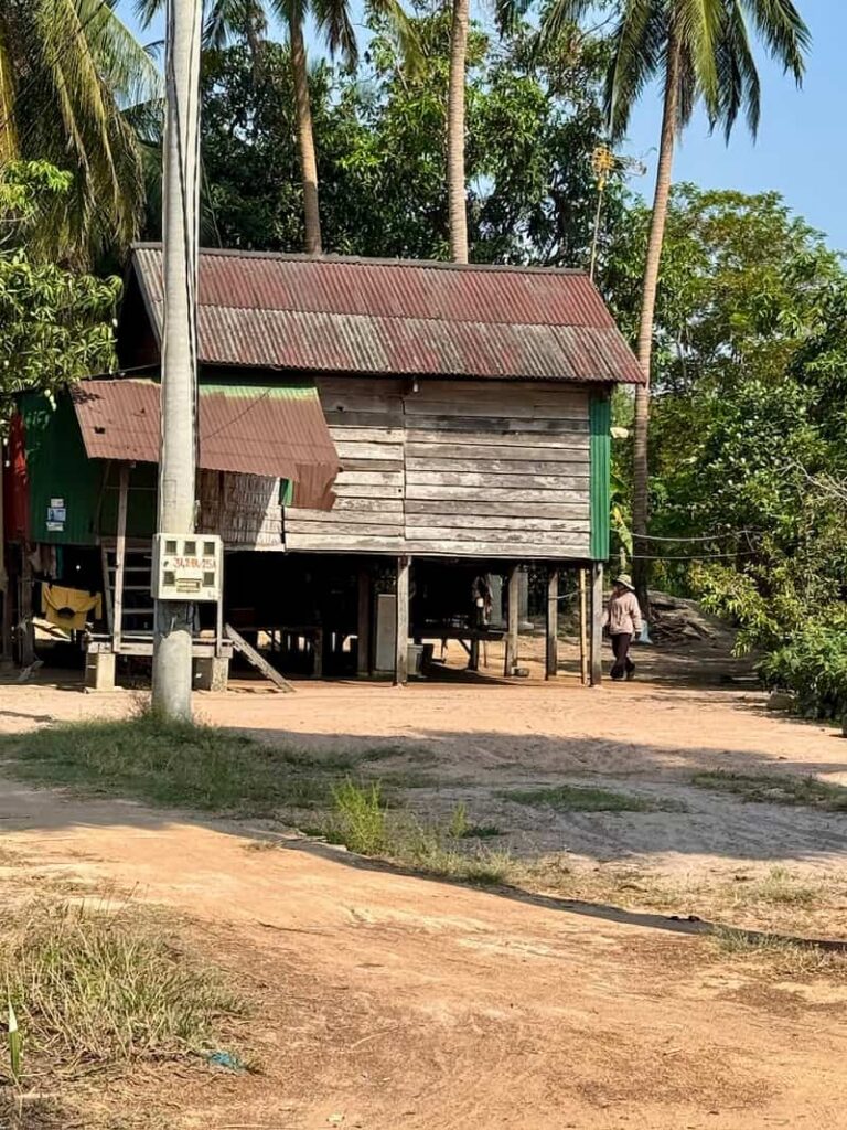 Traditional wooden stilted house with a corrugated metal roof in a rural village near Siem Reap.