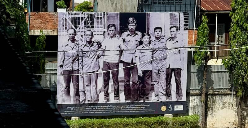 Large outdoor mural showing the historical survivors of the S-21 prison in Phnom Penh, Cambodia.