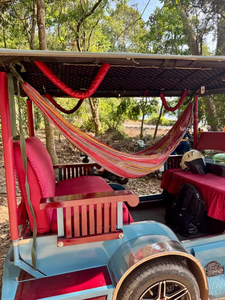 A colorful hammock strung up inside a tuk-tuk, highlighting the Cambodian tradition of resting during the workday.