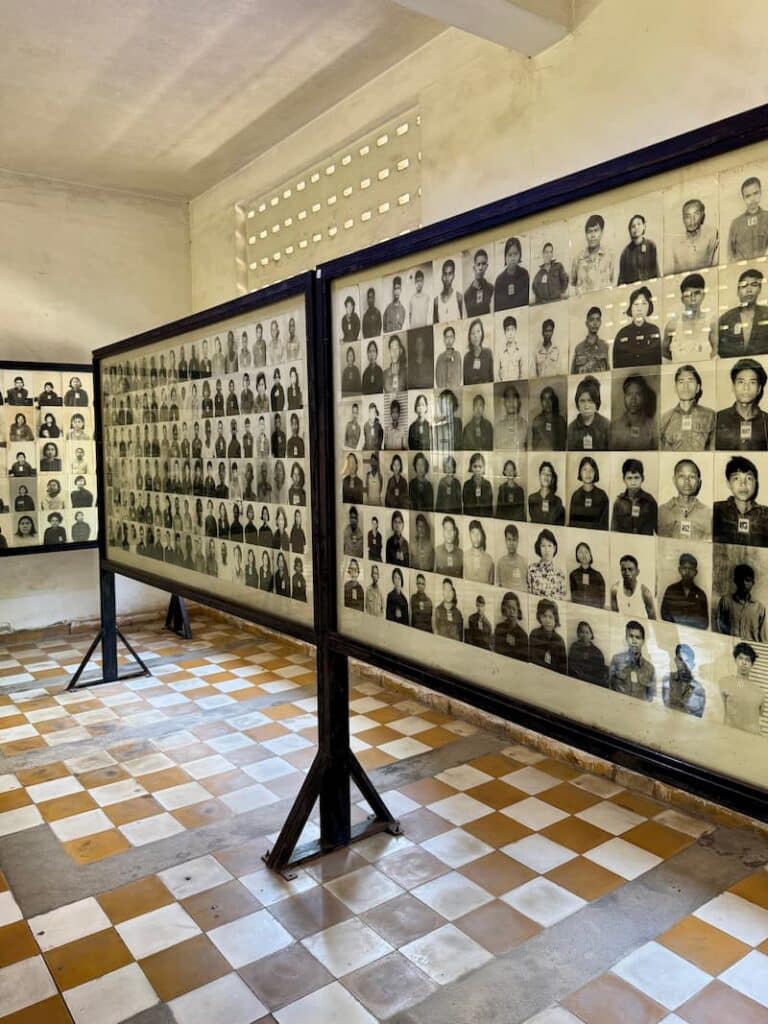 Large display boards holding rows of archival black-and-white prisoner identification photographs inside an exhibition room.