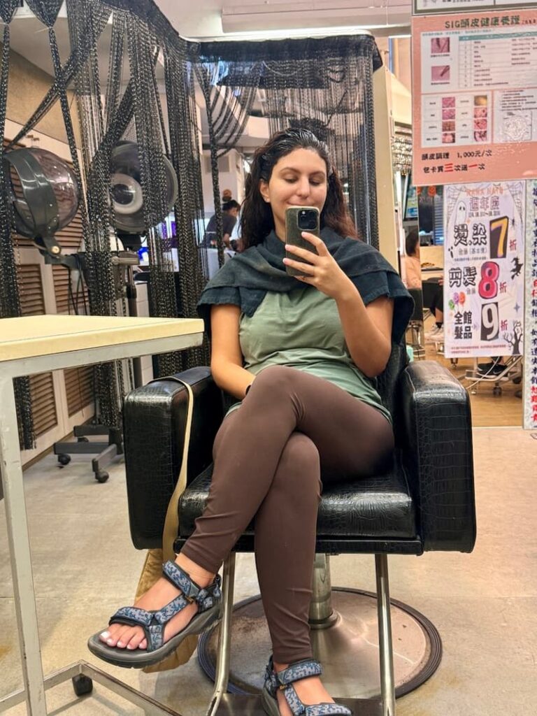 Woman sitting in a hair salon in Taipei taking a mirror selfie during a hair treatment, as featured in our guide about the best eSIMs for Taiwan.