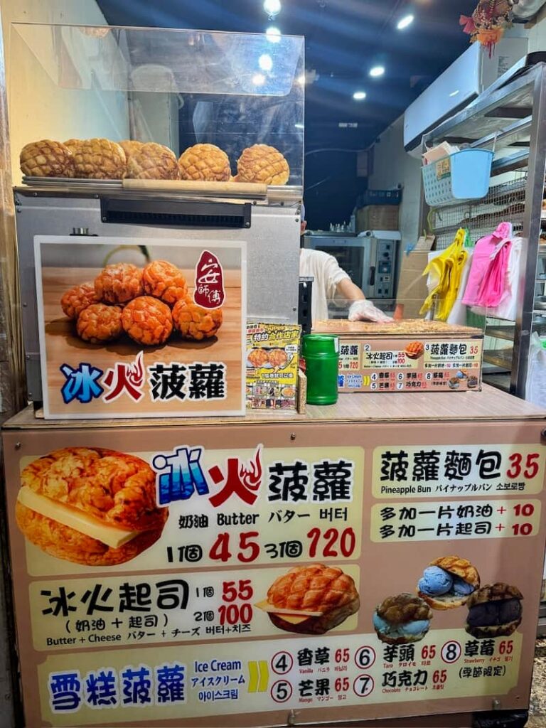 A vibrant night market vendor stall showcasing a detailed menu board for "Ice Fire Pineapple Buns", featuring pricing and options for classic butter, cheese, and multiple ice cream flavors.