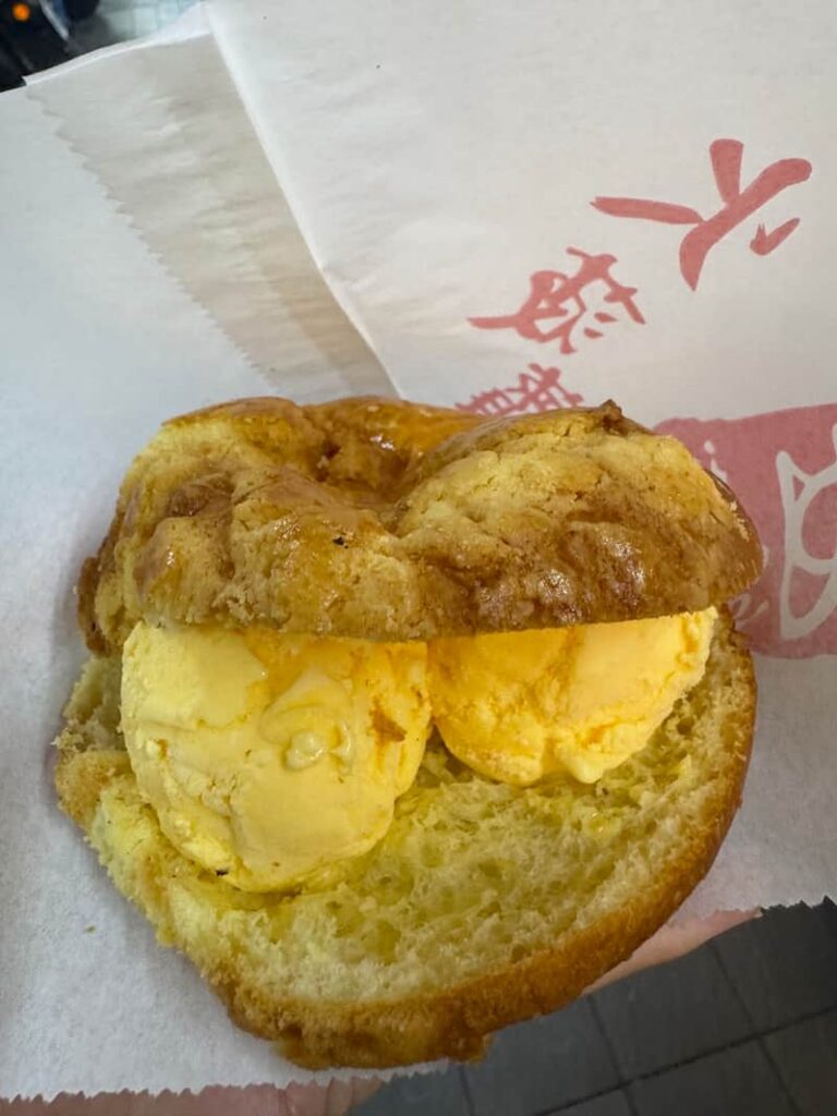 A sweet, golden pastry featuring a crumbly, textured crust split open and stuffed with cold, creamy fillings like traditional melting butter or scoops of ice cream.