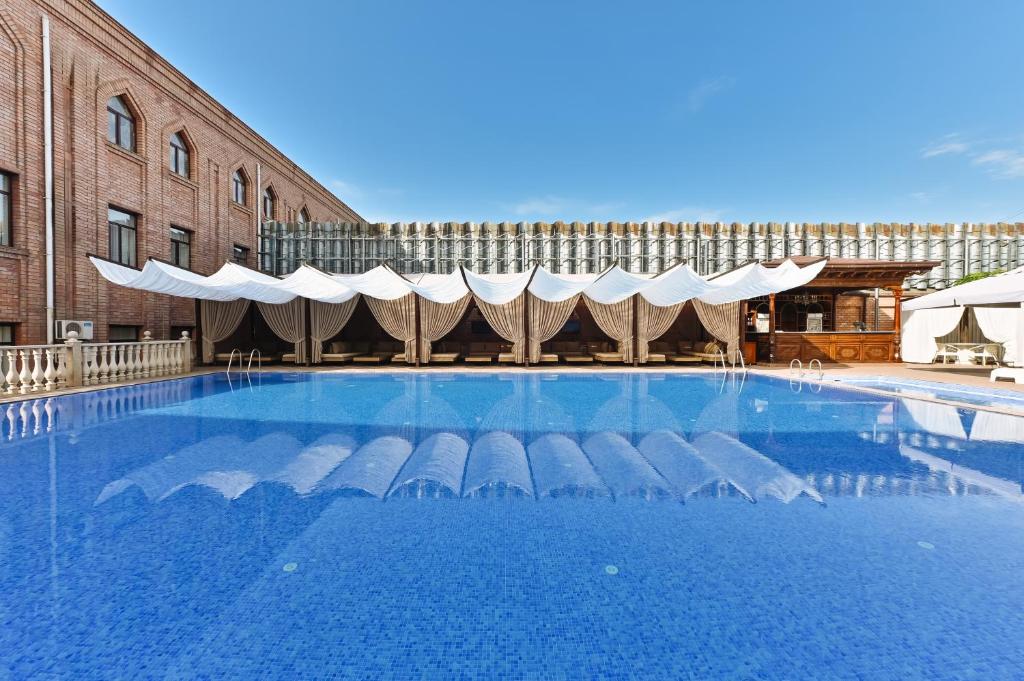 Large outdoor swimming pool and white shaded cabanas at a hotel in Tashkent, as featured in our guide about where to stay in tashkent.