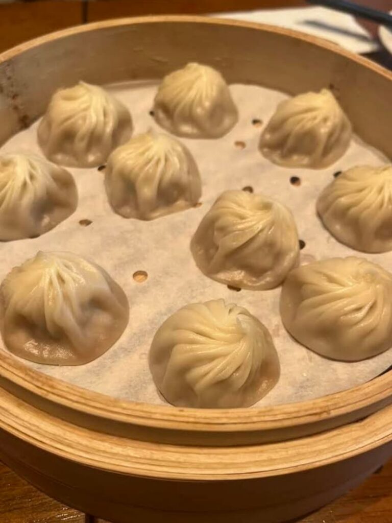 Freshly steamed xiaolongbao soup dumplings arranged in a bamboo basket at a restaurant in Taipei.