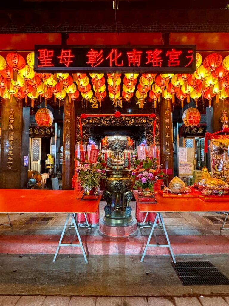 A traditional Taiwanese temple entrance adorned with glowing red lanterns and ceremonial tables.