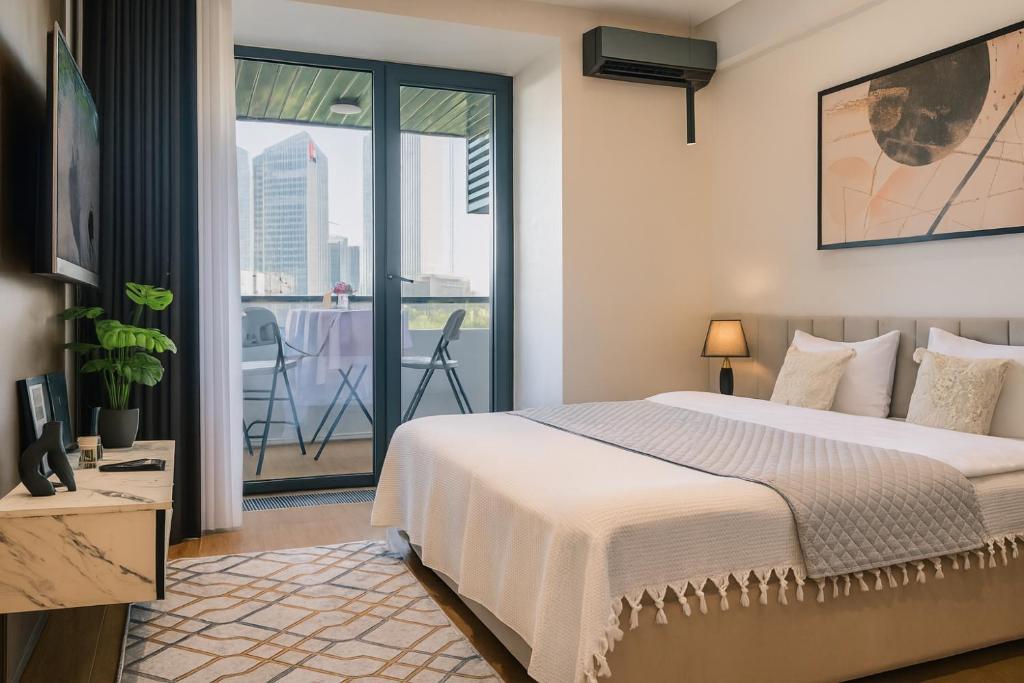 Clean and modern studio apartment bedroom with balcony access and city views at U-Tower in Tashkent.
