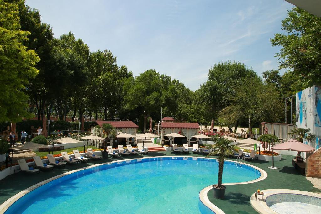 Curved outdoor swimming pool, sun loungers, and shady cabanas at the Wyndham Tashkent hotel.